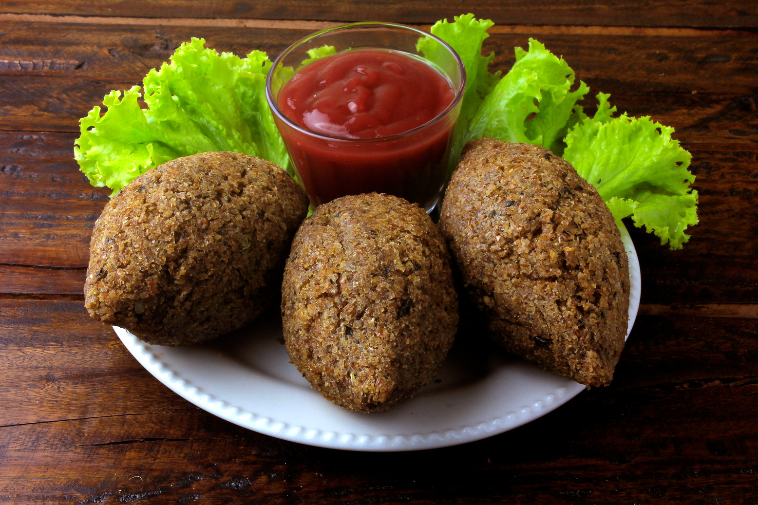 Fried Kibbeh with Tomato Sauce on a Plate, over Rustic Wooden Table