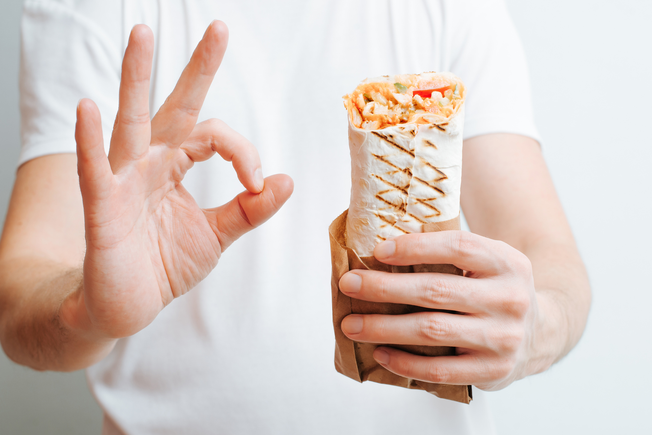 Close-up caucasian man holding shawarma, kebab or doner and showing ok gesture