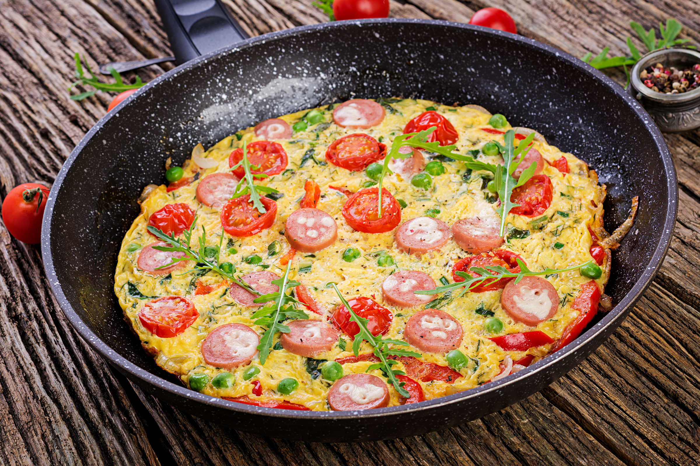 Omelette with tomatoes, sausage and green peas  in rustic style.  Frittata - italian omelet.